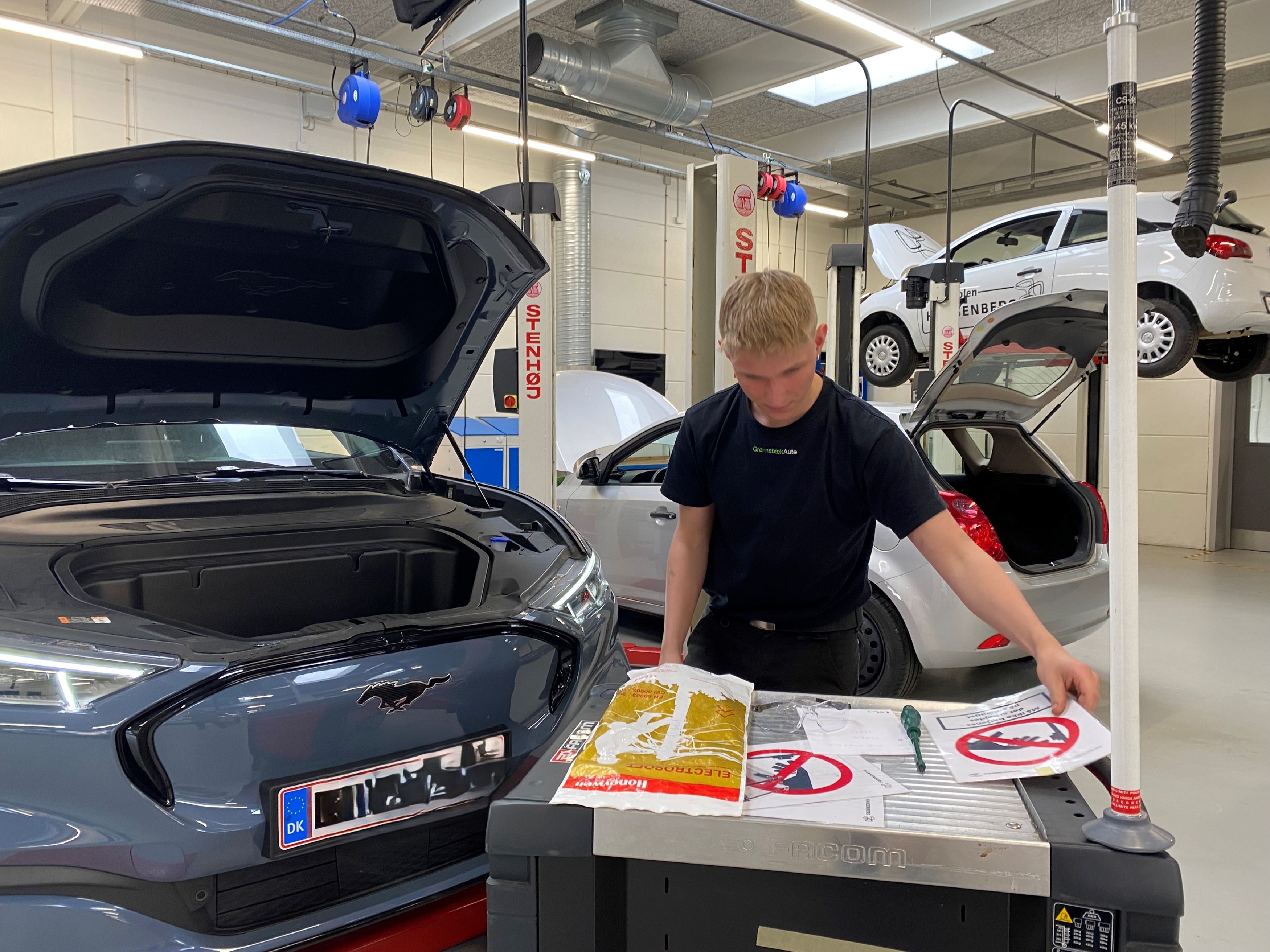 Personvognsmekanikerlærlingen træner på en elbil på skolens autoværksted, inden han skal deltage ved DM i Skills.