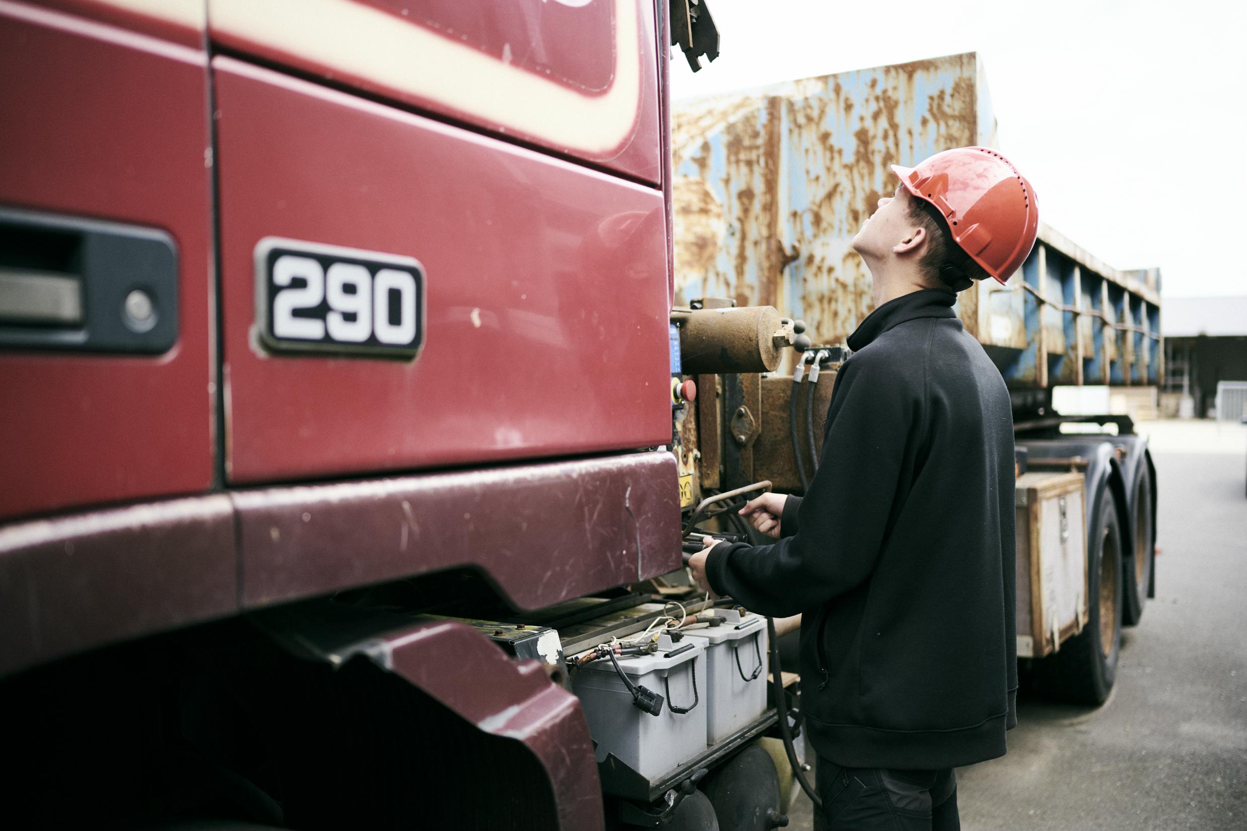 En lastbilchaufførelev på vejgodstransportuddannelsen styrer kranen på en lastbil.
