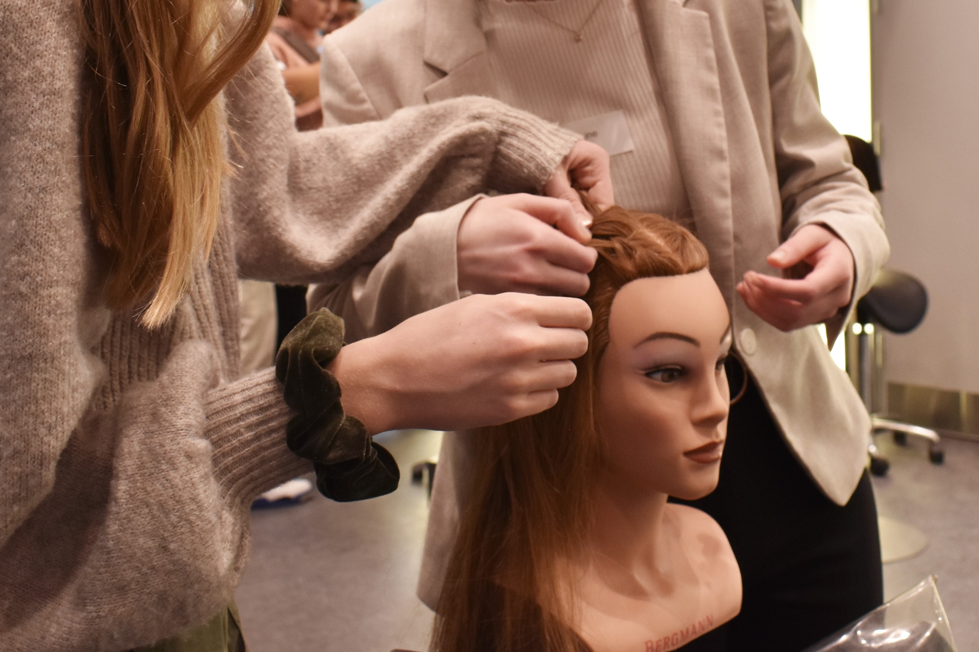 Til Prøv et fag for elever i 4.-10. klasse, er der nogle af deltagerne der er ved at flette hår på et frisørhoved.