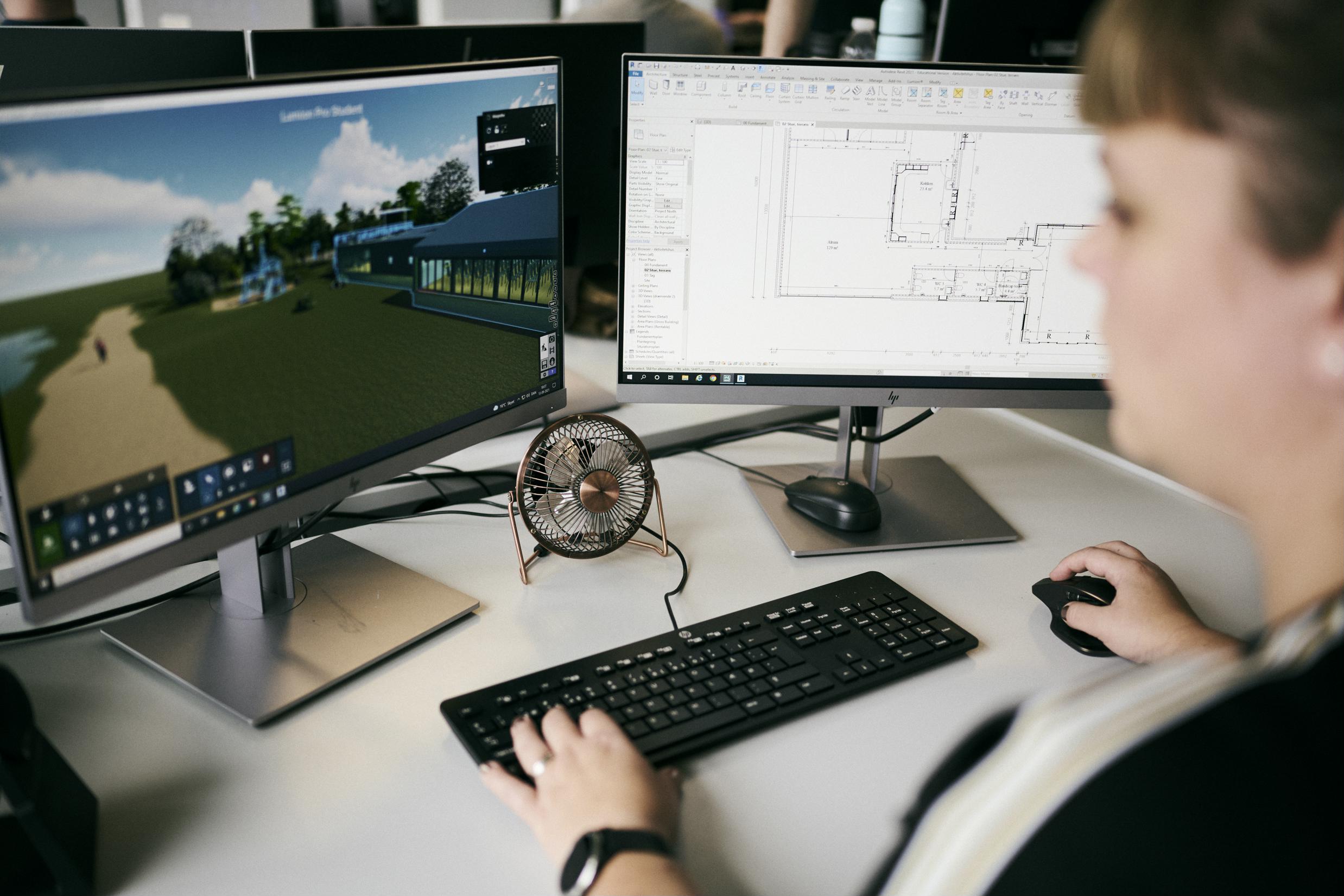 En teknisk designerelev er ved at designe en bygning og kan se sin plantegning på den ene skræm og 3D-tegning på den anden skærm.