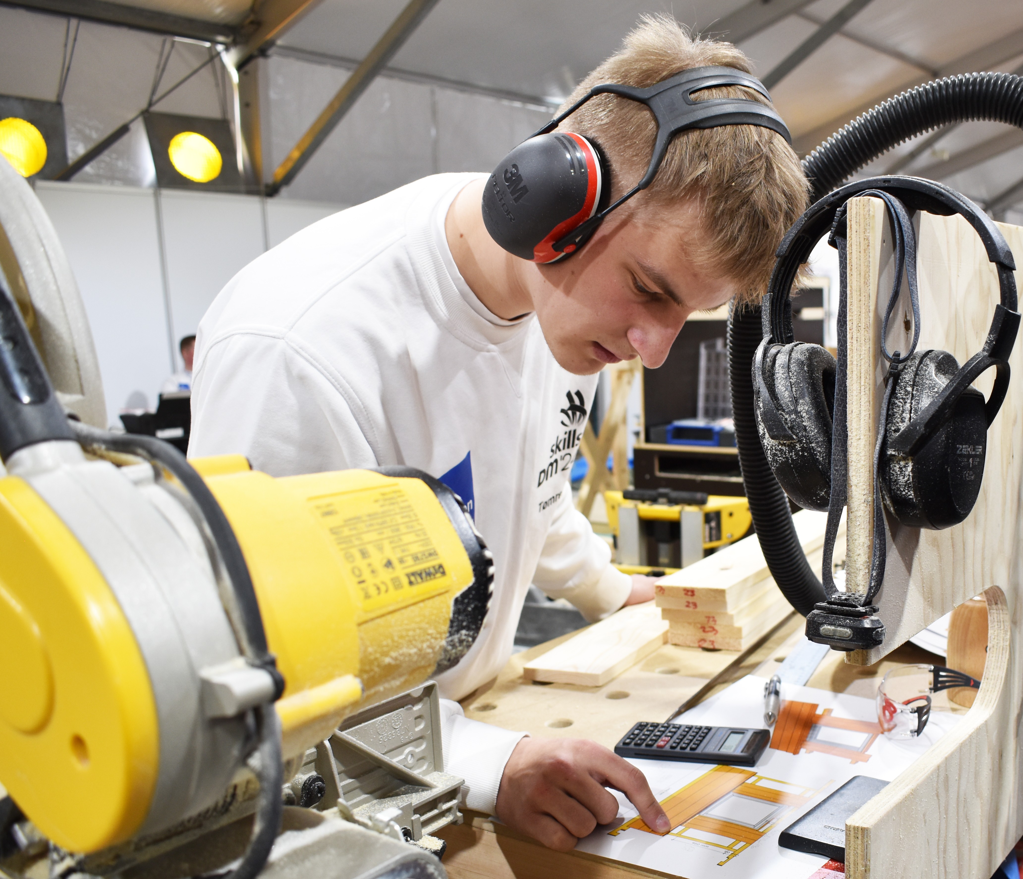 Toke, der er tømrerelev studerer tegningerne til hans byggeopgave under DM i Skills 2024.