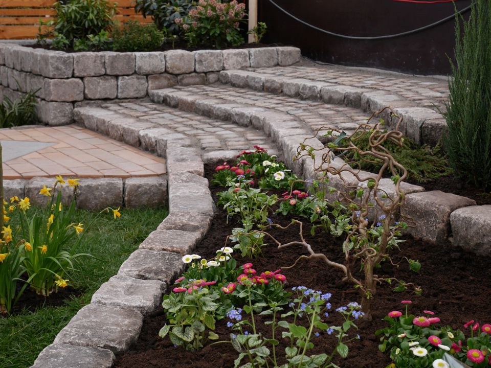 Nogle anlægningsgartnerelever har skabt et smukt uderum ved at anlægge blomsterbede og trappetrin i brosten