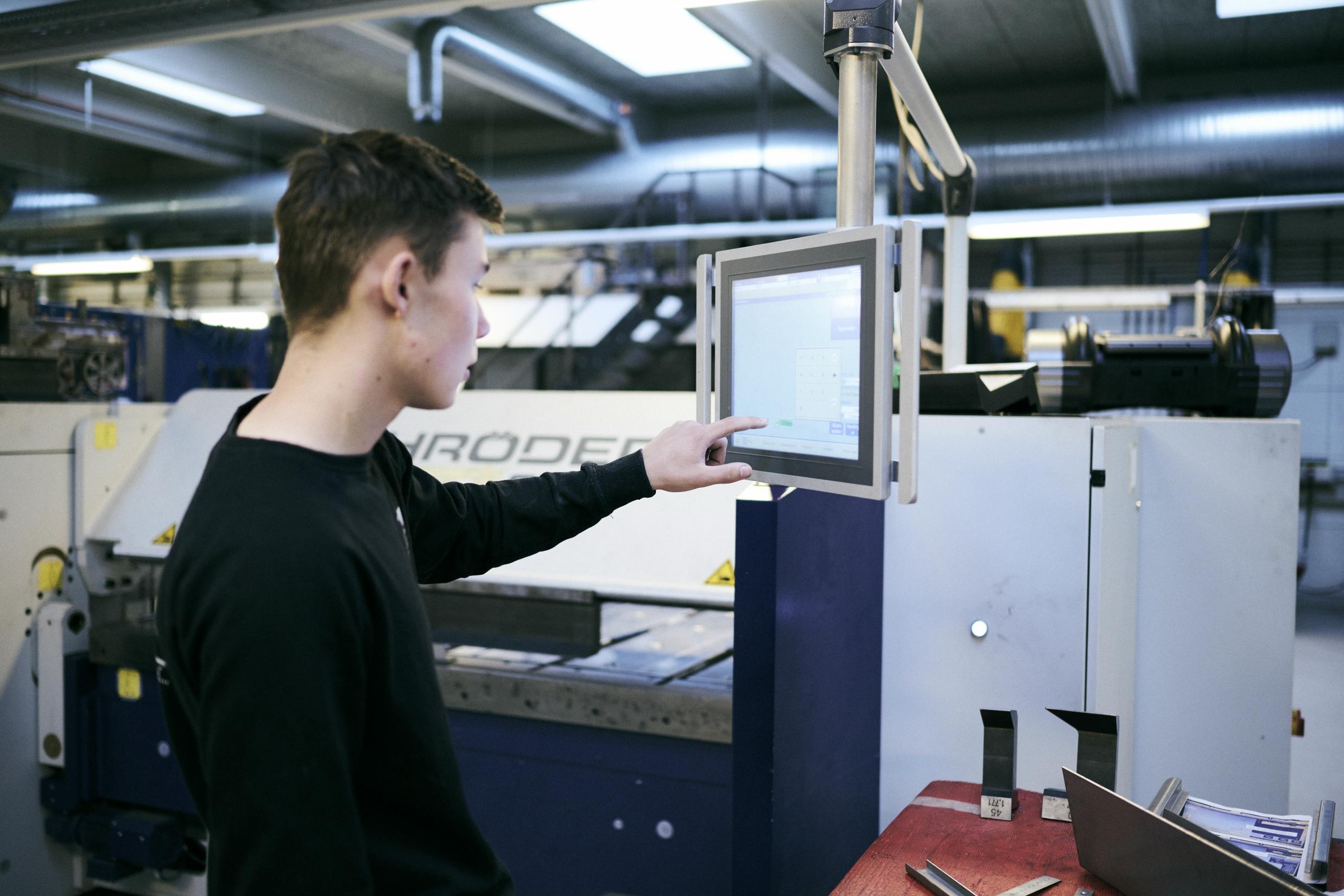 En smedeelev programmerer en bukkemaskine på Hansenbergs smedeværksted.