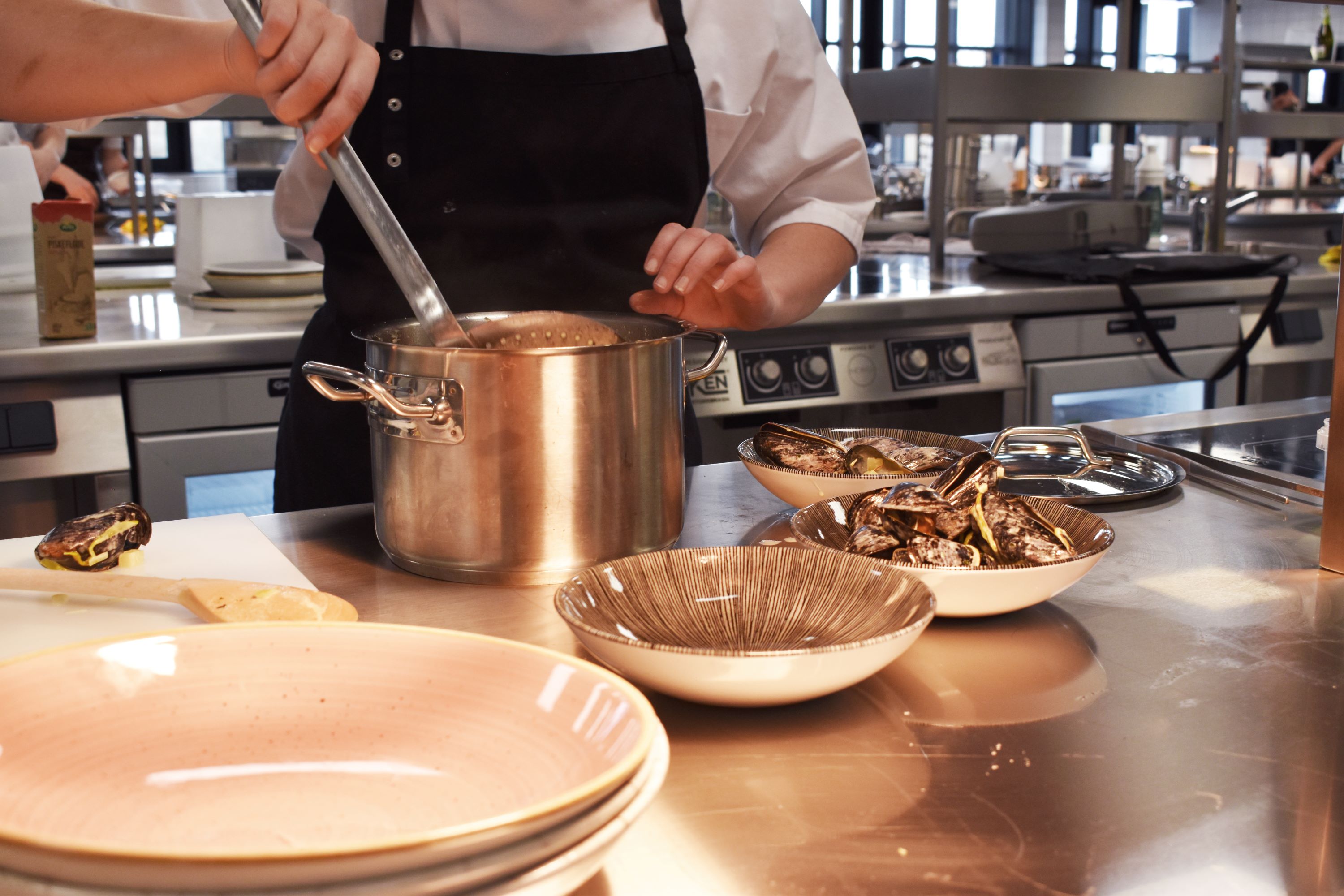 Muslingerne er færdigtilberedt og skal nu anrettes og serveres for kokkeelevernes gæster i skolens undervisningsrestaurant.