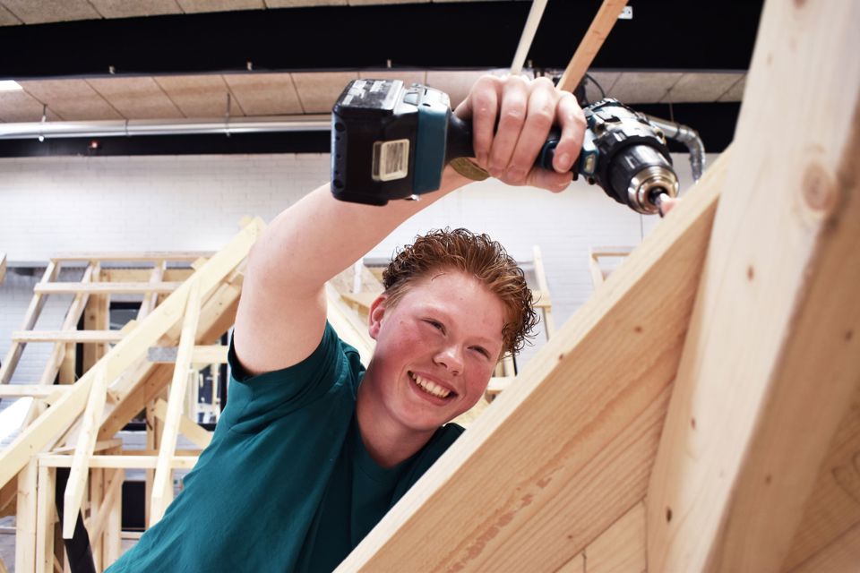 Tømrerlærling Maria Mærsk Hansen er ved at bygge et udsnit af en hytte på Hansenbergs tømrerværksted.