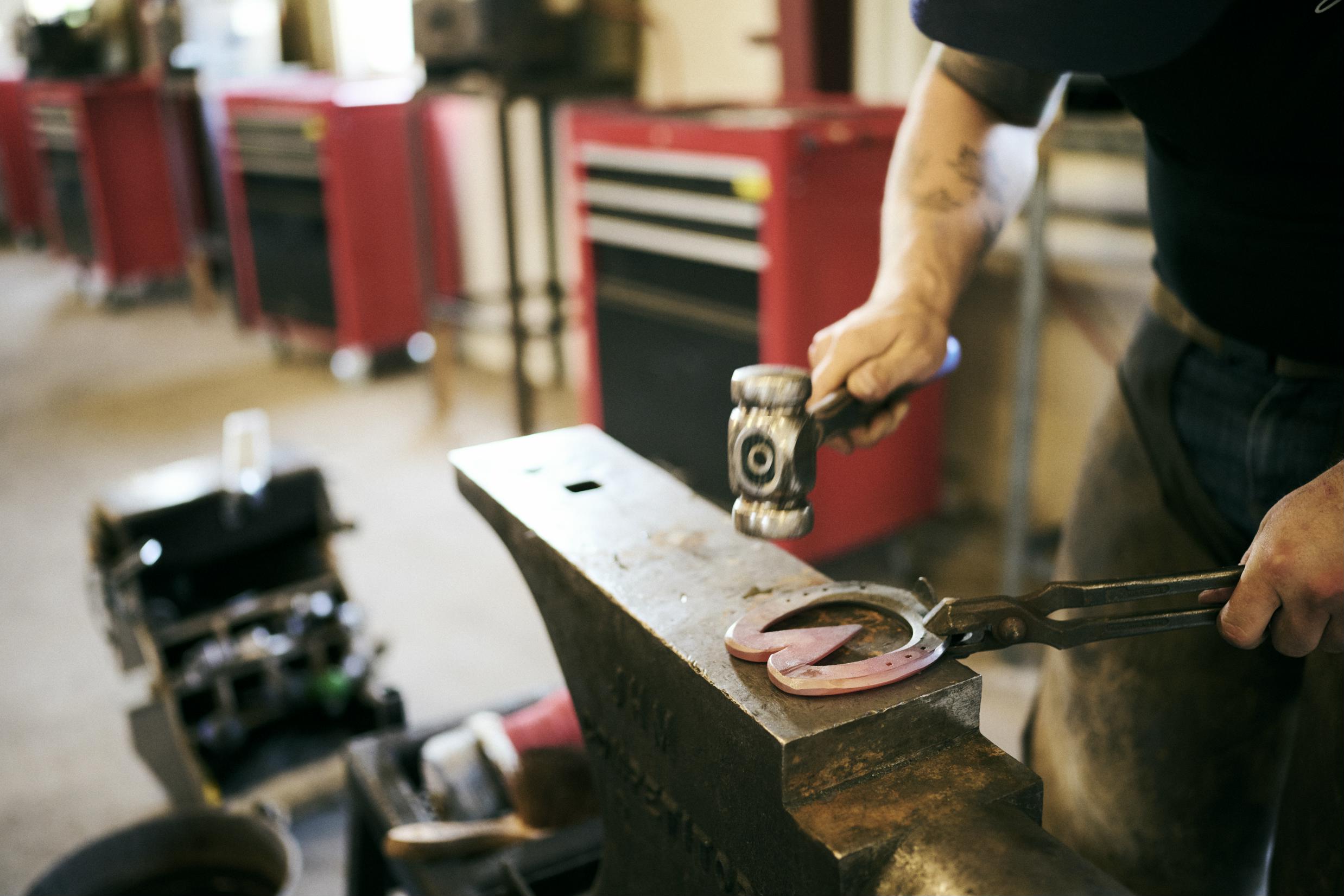 En beslagsmedelærling smeder en speciel hestesko i Hansenbergs beslagsmedje.