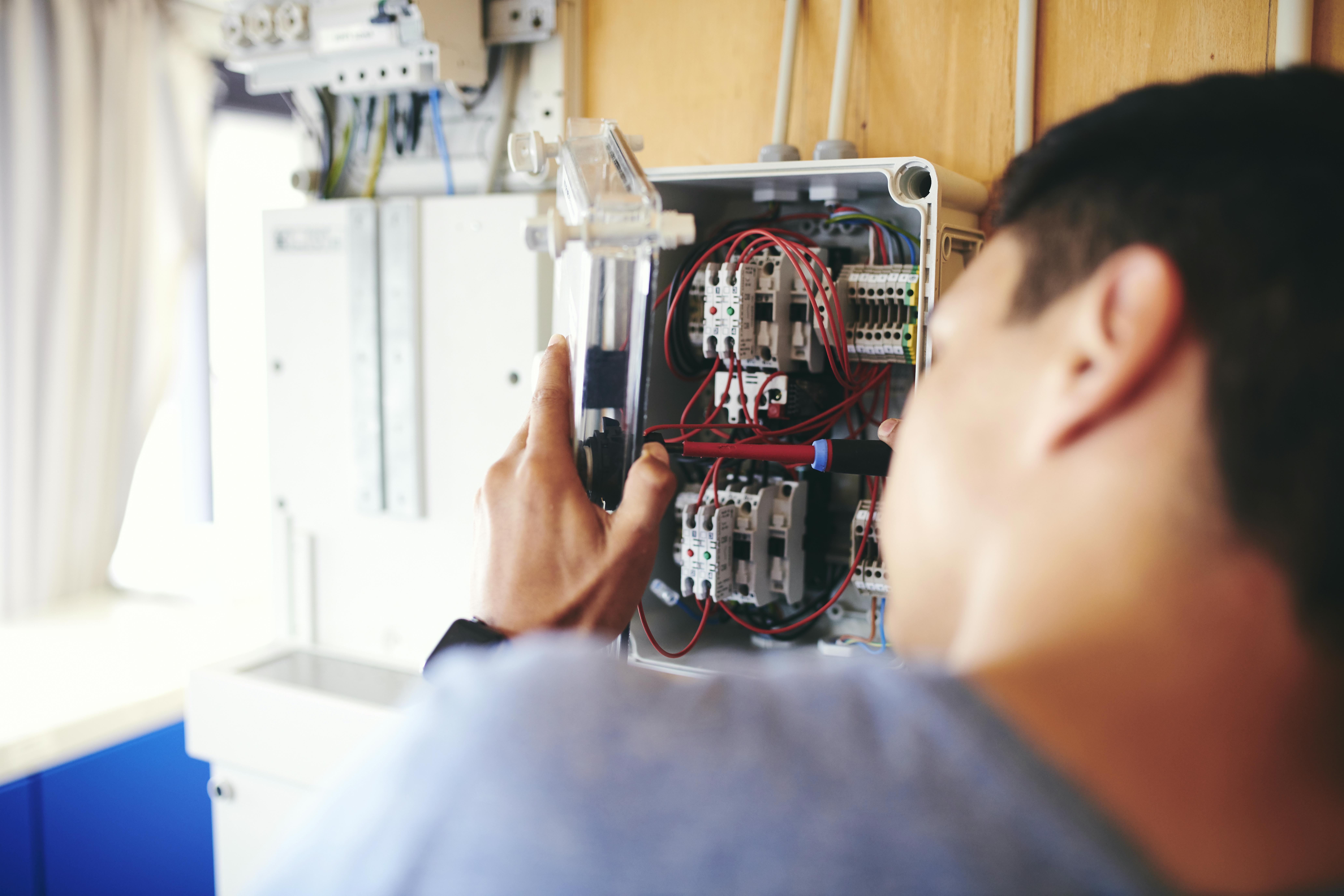 En elektrikerelev tilslutter ledningerne i en eltavle.
