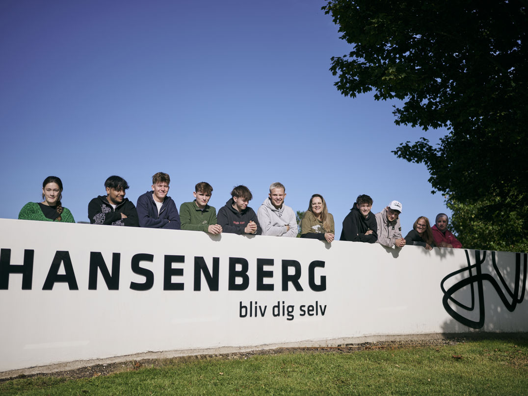Studiemiljøet på Hansenberg – en flok hjælpsomme elever stiller gerne op til et billede ved skolens stenskilt.