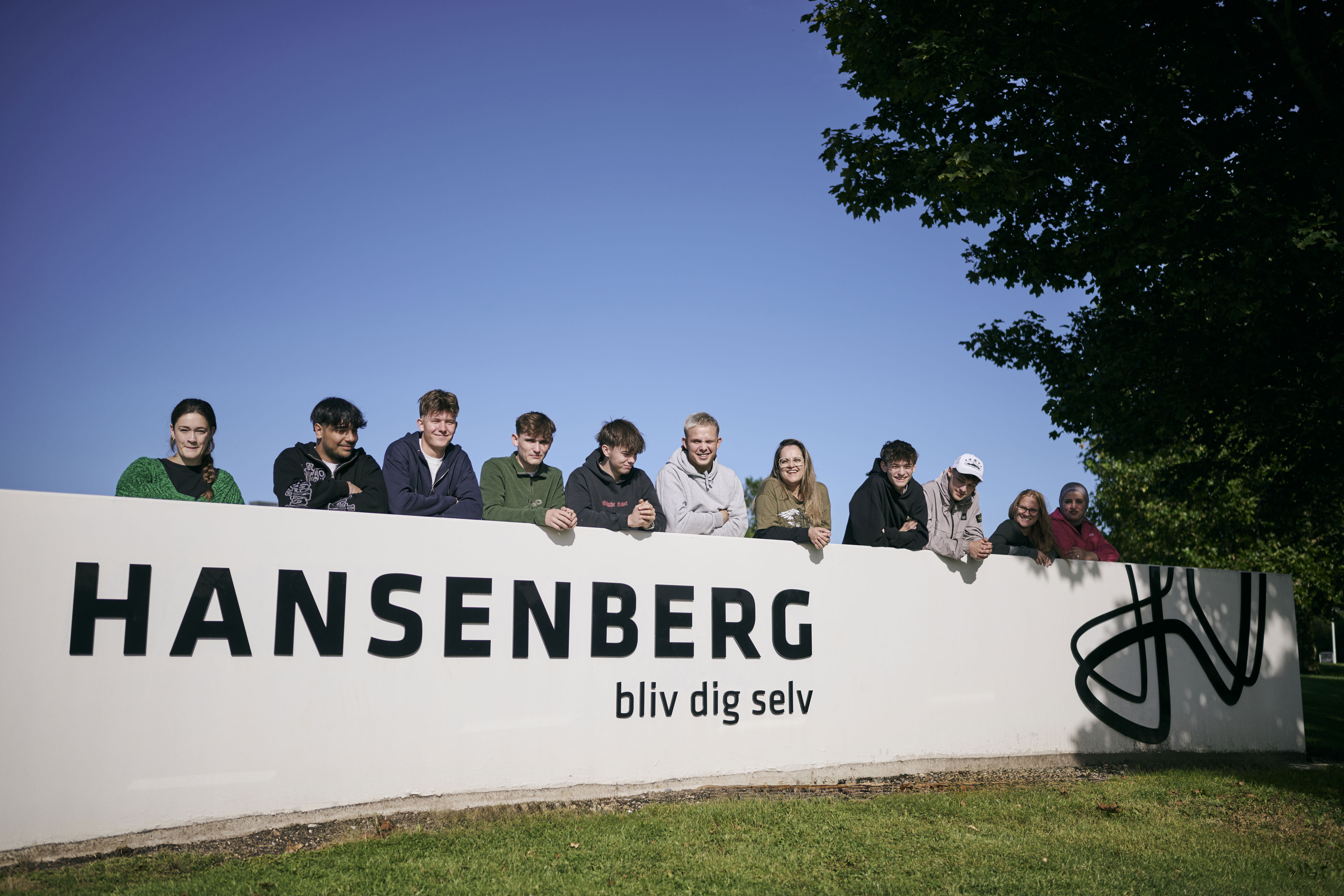 Studiemiljøet på Hansenberg – en flok hjælpsomme elever stiller gerne op til et billede ved skolens stenskilt.