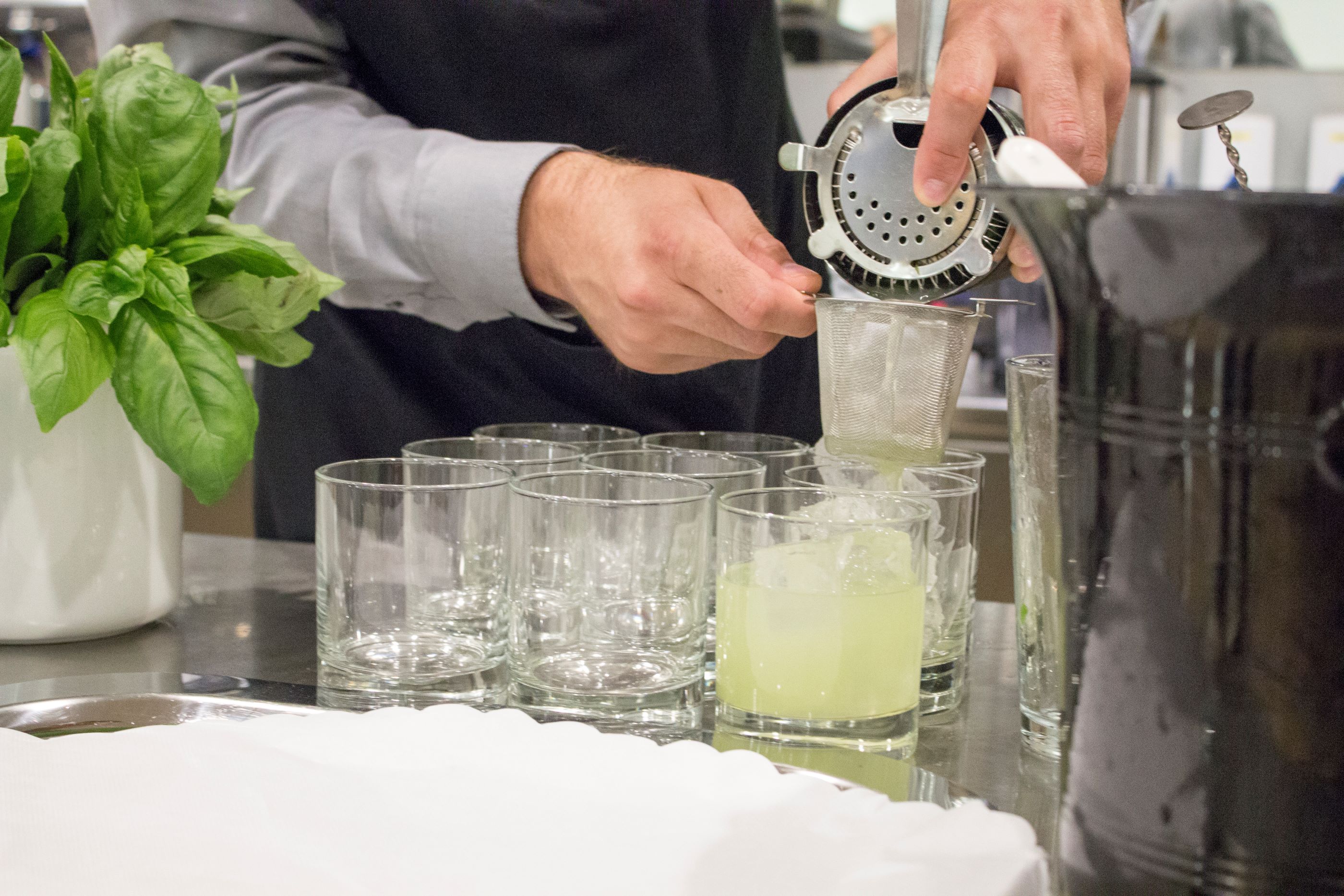 En tjenerelev blander drinks til servering for et selskab.