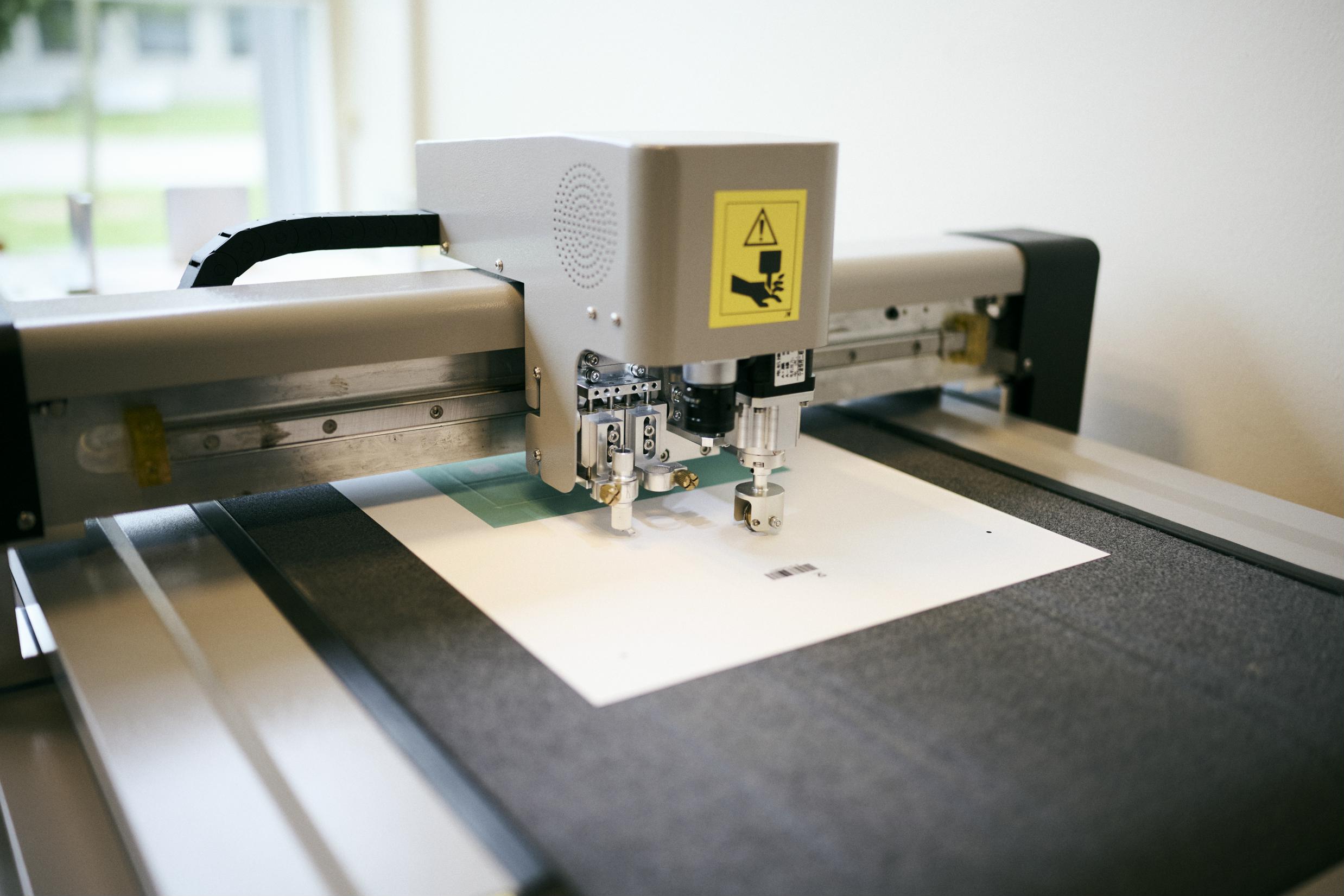 Den digitale skæremaskine på skolens mediegrafikeruddannelse kan skære meget præcist ud efter elevernes design.