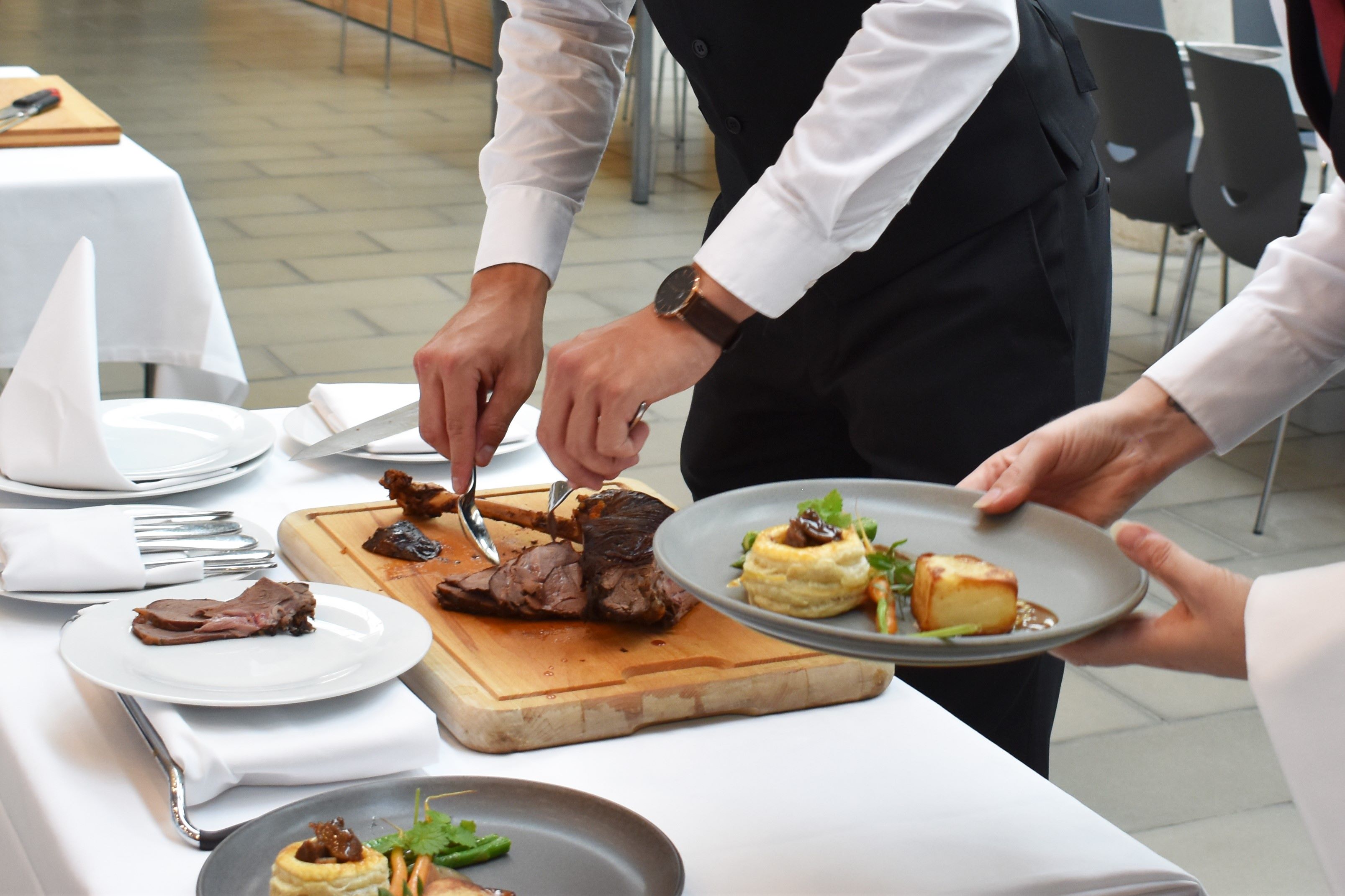 To tjenerelever anretter maden på smukkeste vis til tallerkenservering.