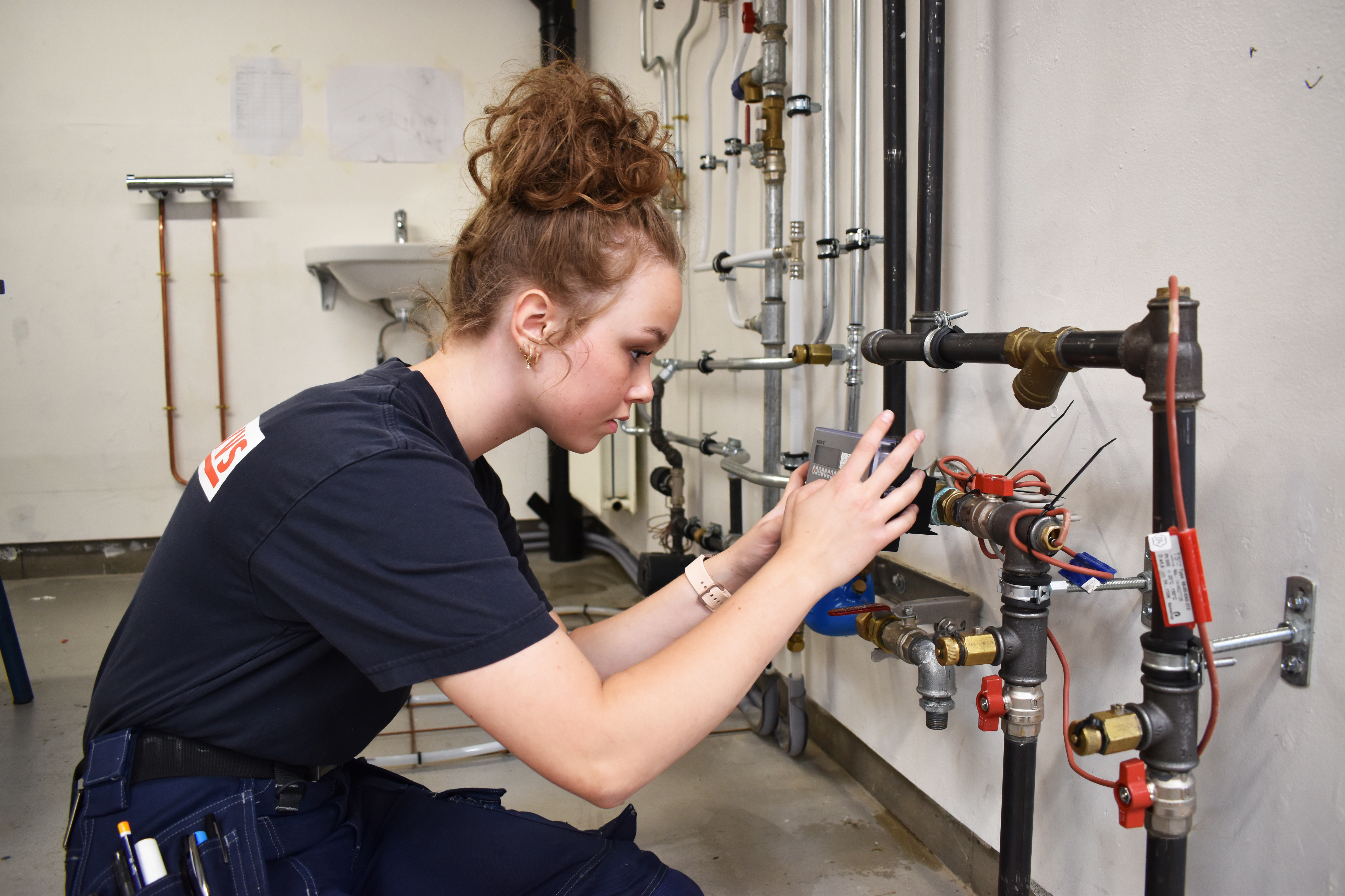 Thea Juul Harder Qvist er i lære som VVS-energispecialist, og hun arbejder her på en installation i VVS-værkstedet.