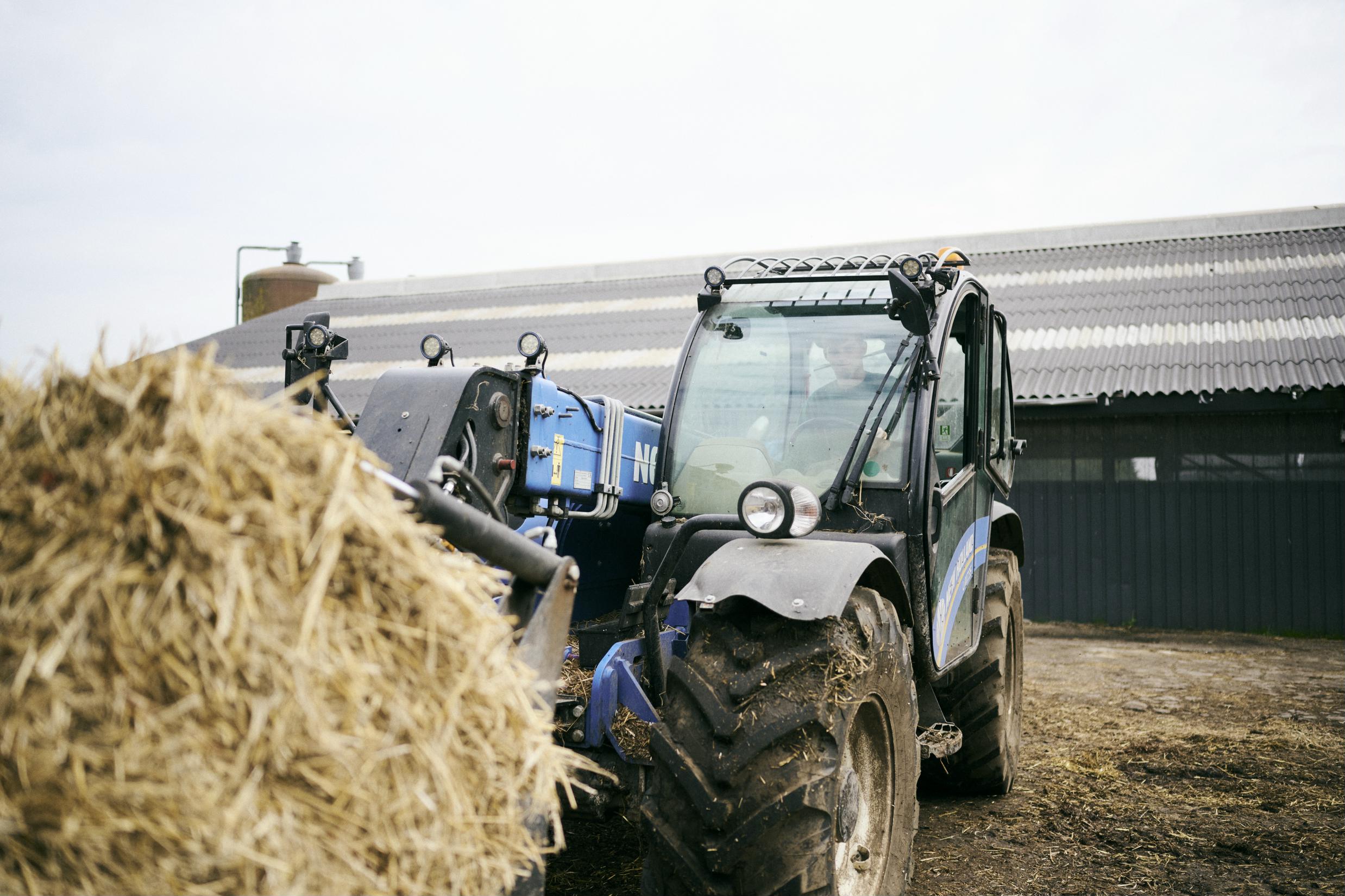 En landbrugselev på Hansenbergs teleskoplæsser henter en bigballe til køernes løsdriftsstald.