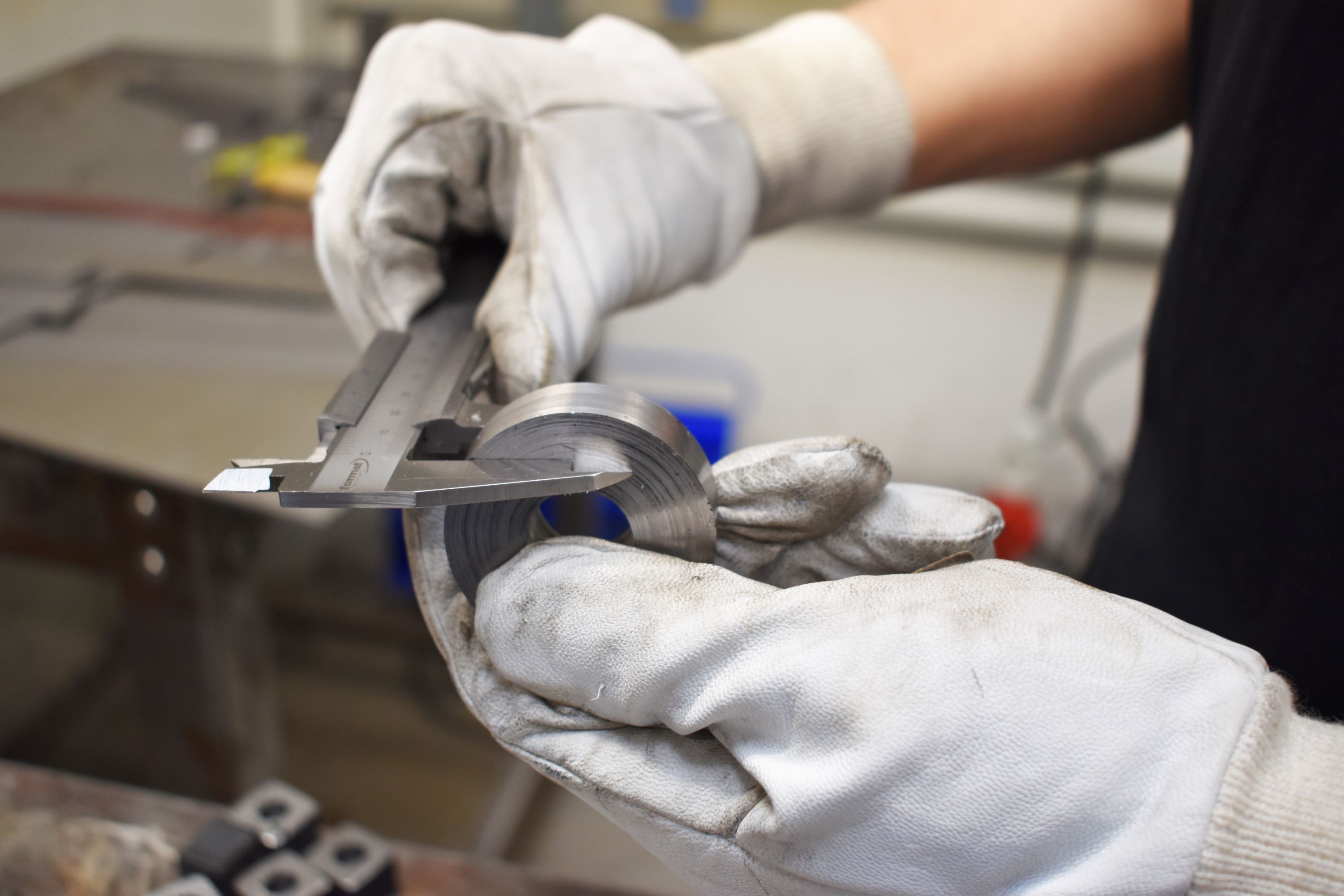 En EUX-smedelærling måler efter med en skydelære, da målene skal være helt præcise.