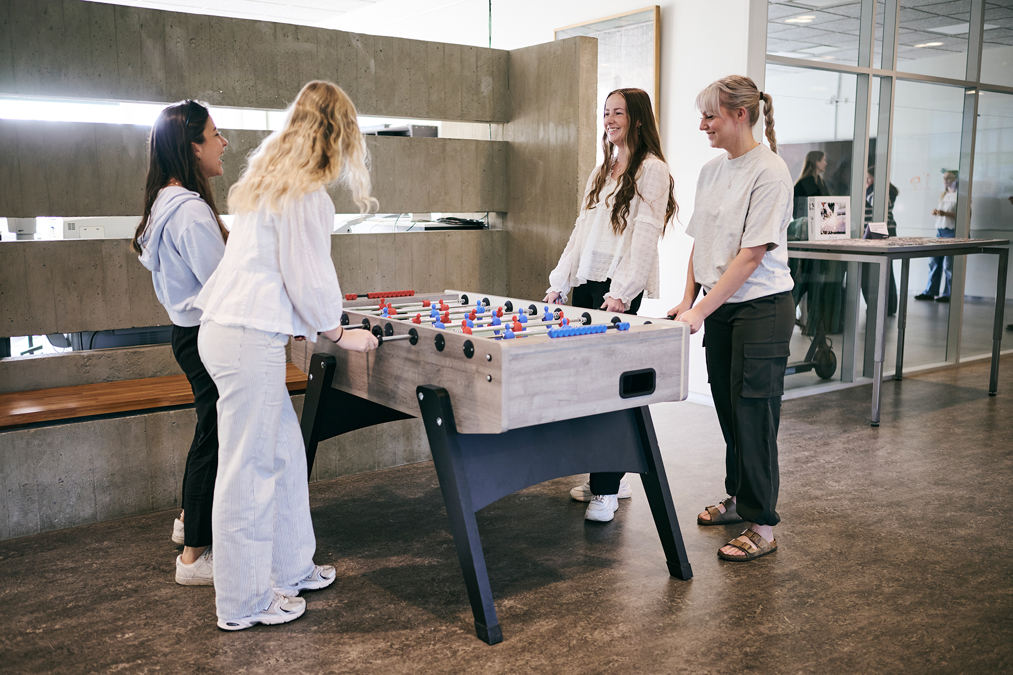 Pigerne hygger og griner over et spil bordfodbold i pausen.