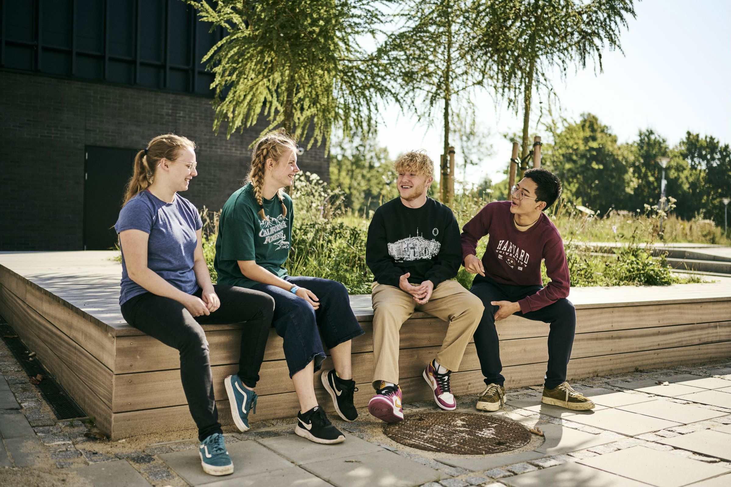 4 HTX-elever hygger sammen i pausen ude i det gode vejr - alle kan tale med alle på Hansenberg Tekniske Gymnasium, som de siger.