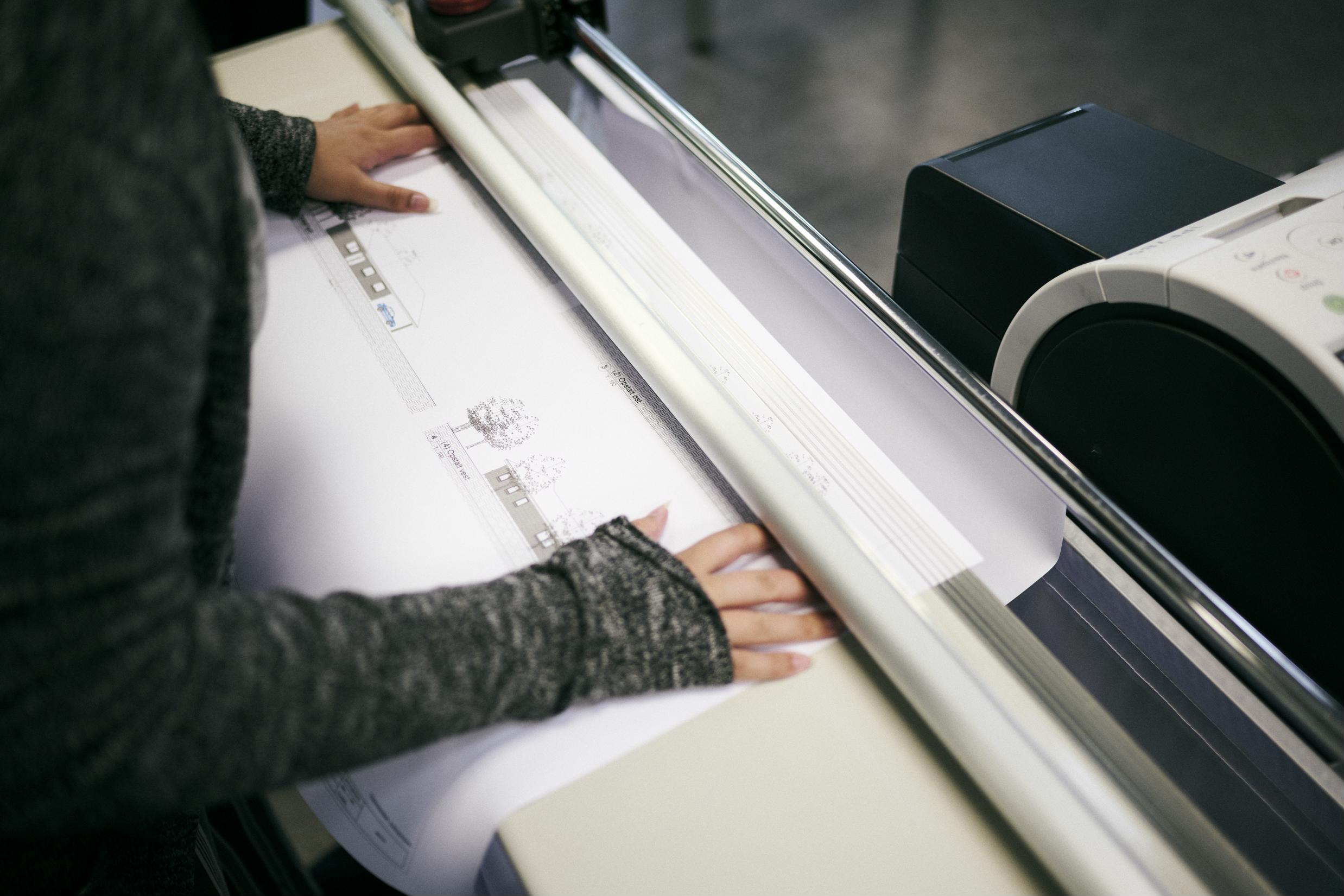 En elev på uddannelsen til teknisk designer printer plantegning og hustegning på storformat.