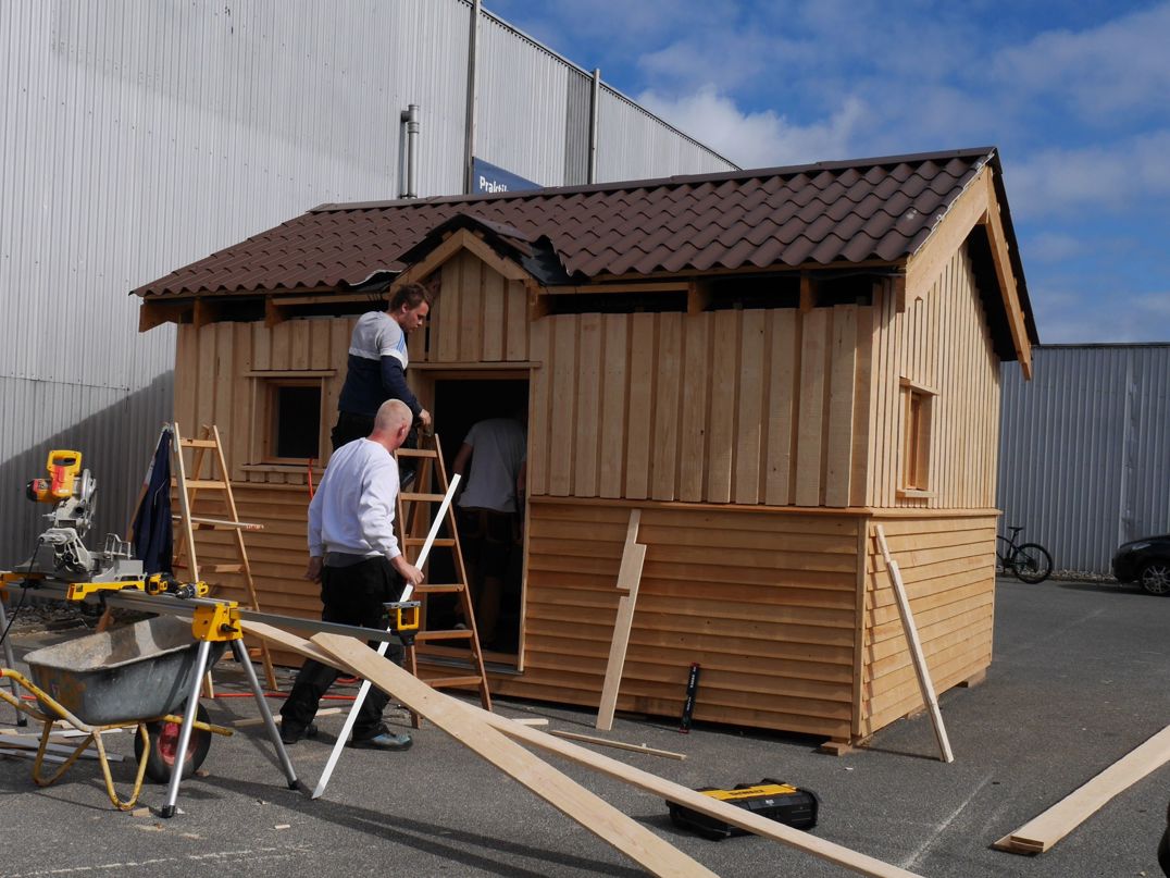 tre elever på Hansenbergs tømreruddannelse hjælpes ad med at bygge et annekshus i træ.