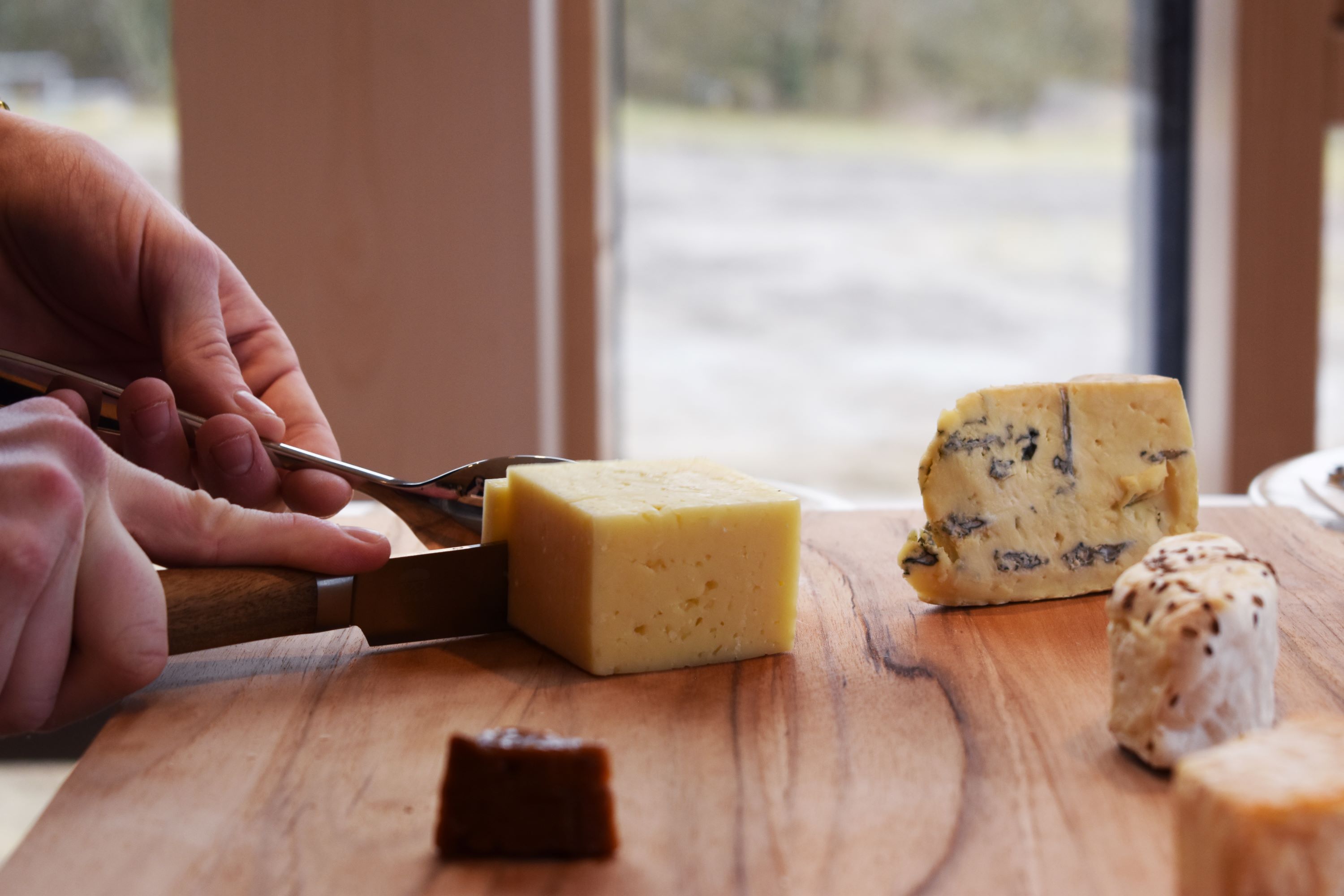 En elev på Hansenbergs tjeneruddannelse skærer skærer ost til en osteanretning.