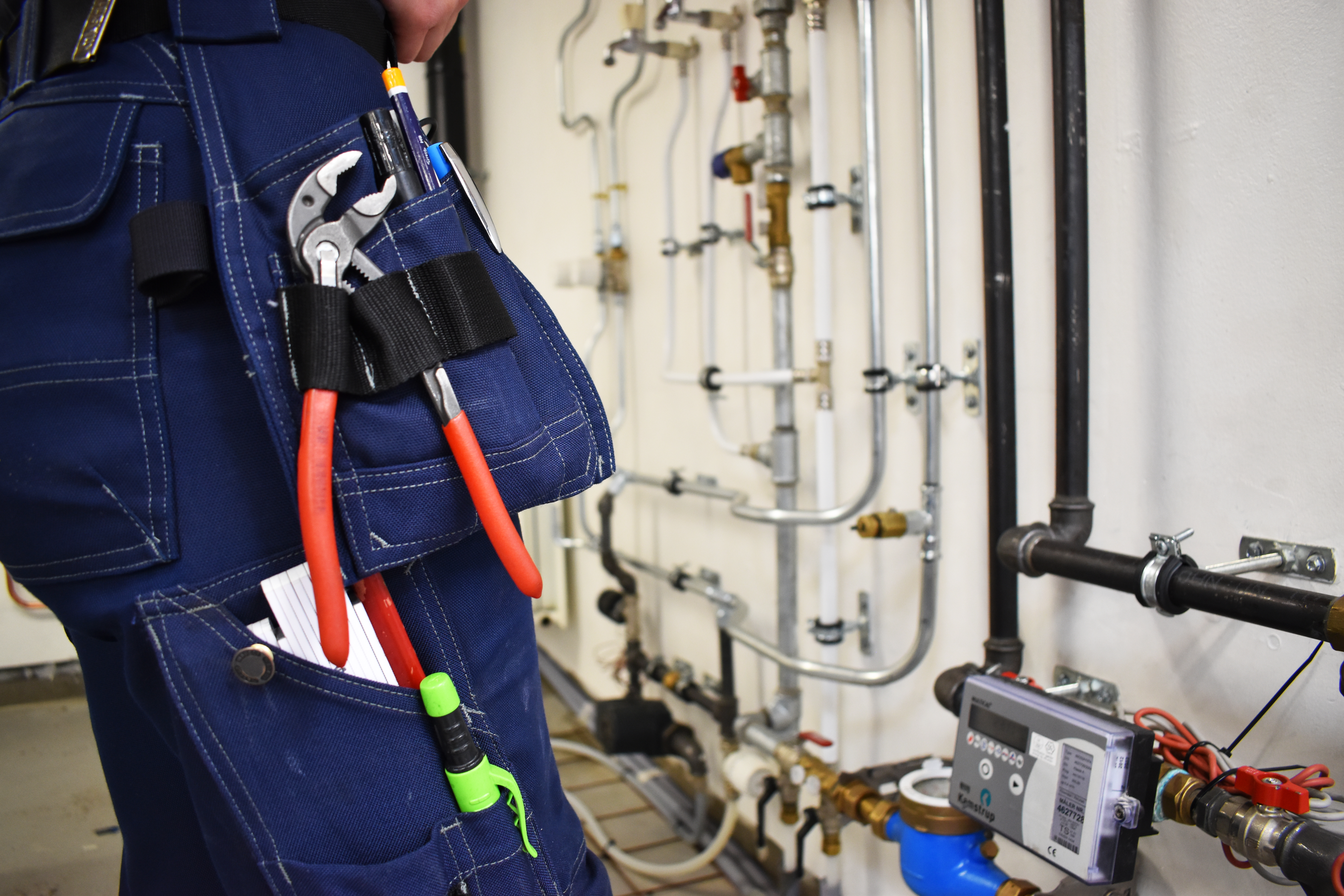 Thea Juul Harder Qvist er i lære som VVS-energispecialist, og hun står her foran en installation i VVS-værkstedet.