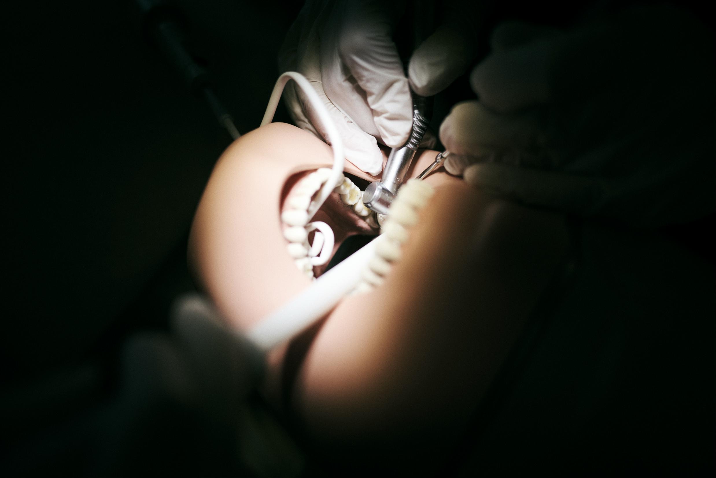 Tandklinikassistenteleverne øver sig i at bore og suge på en tanddukke i Hansenbergs tandklinik.