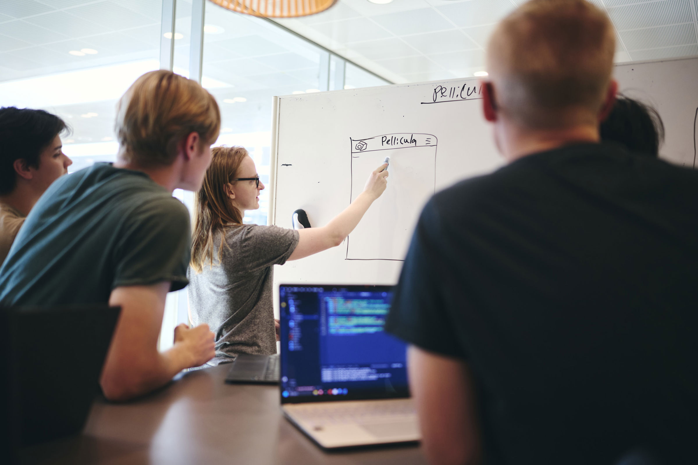 En gruppe elever pÄ Hansenberg Tekniske Gymnasium har gruppearbejde i programmering, og en af eleverne skriver pÄ tavlen.