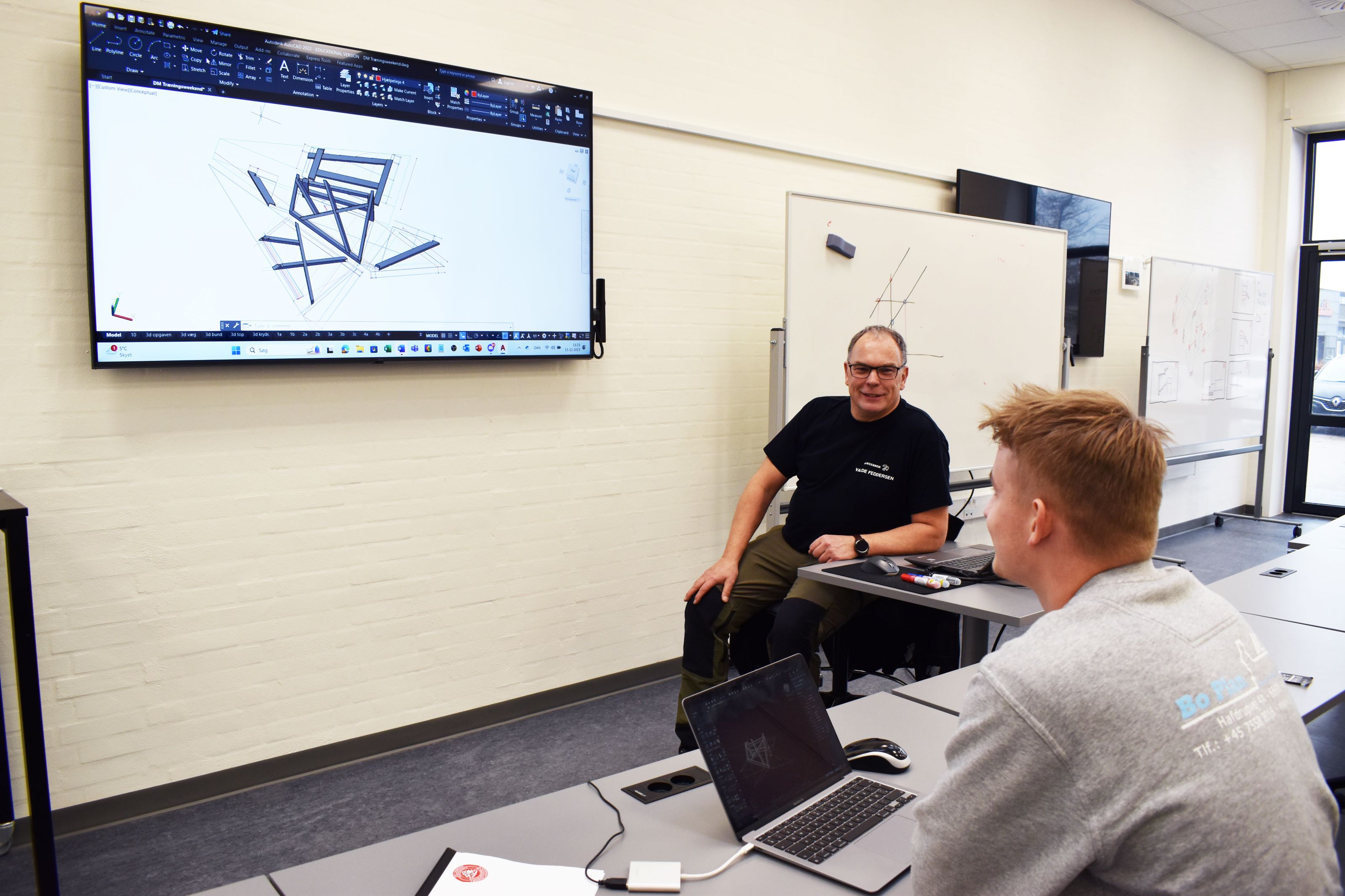 En tømrerlærling har teori med en tømrerfaglærer på den digitale skærm i et undervisningslokale på Hansenberg.