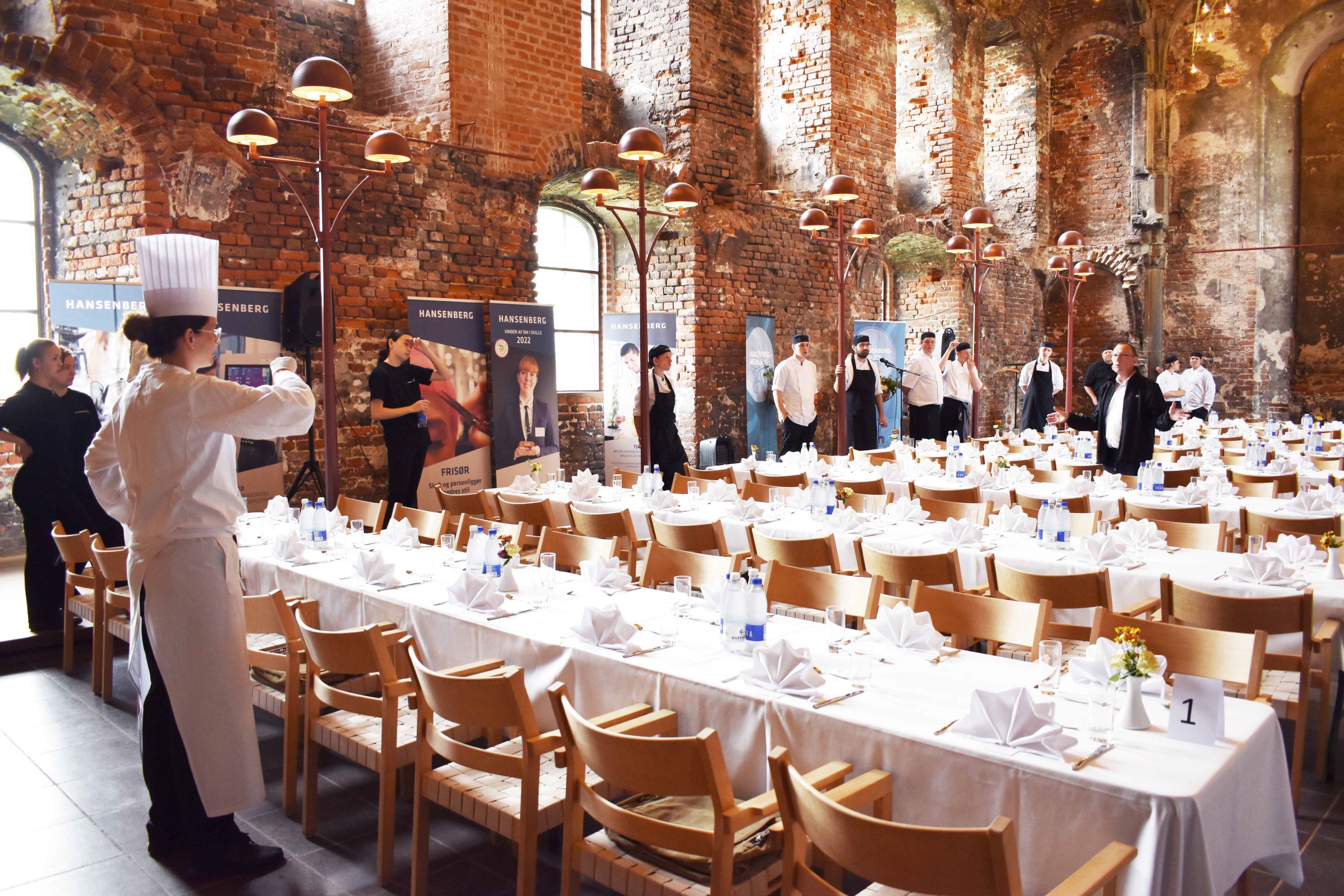 Tjener- og kokkefaglærererne inspicerer elevernes opdækning til Hansenberg-medaljen på Koldinghus.