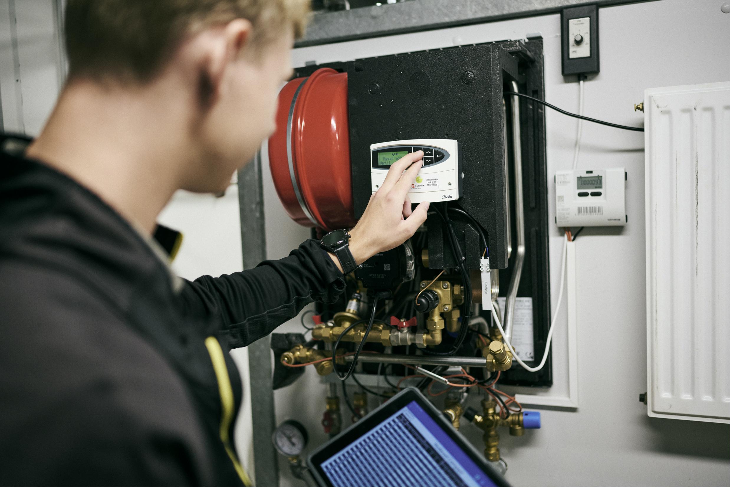 En vvs-energispecialistlærling indstiller et af skolens mange anlæg med hjælp fra en app på en tablet.