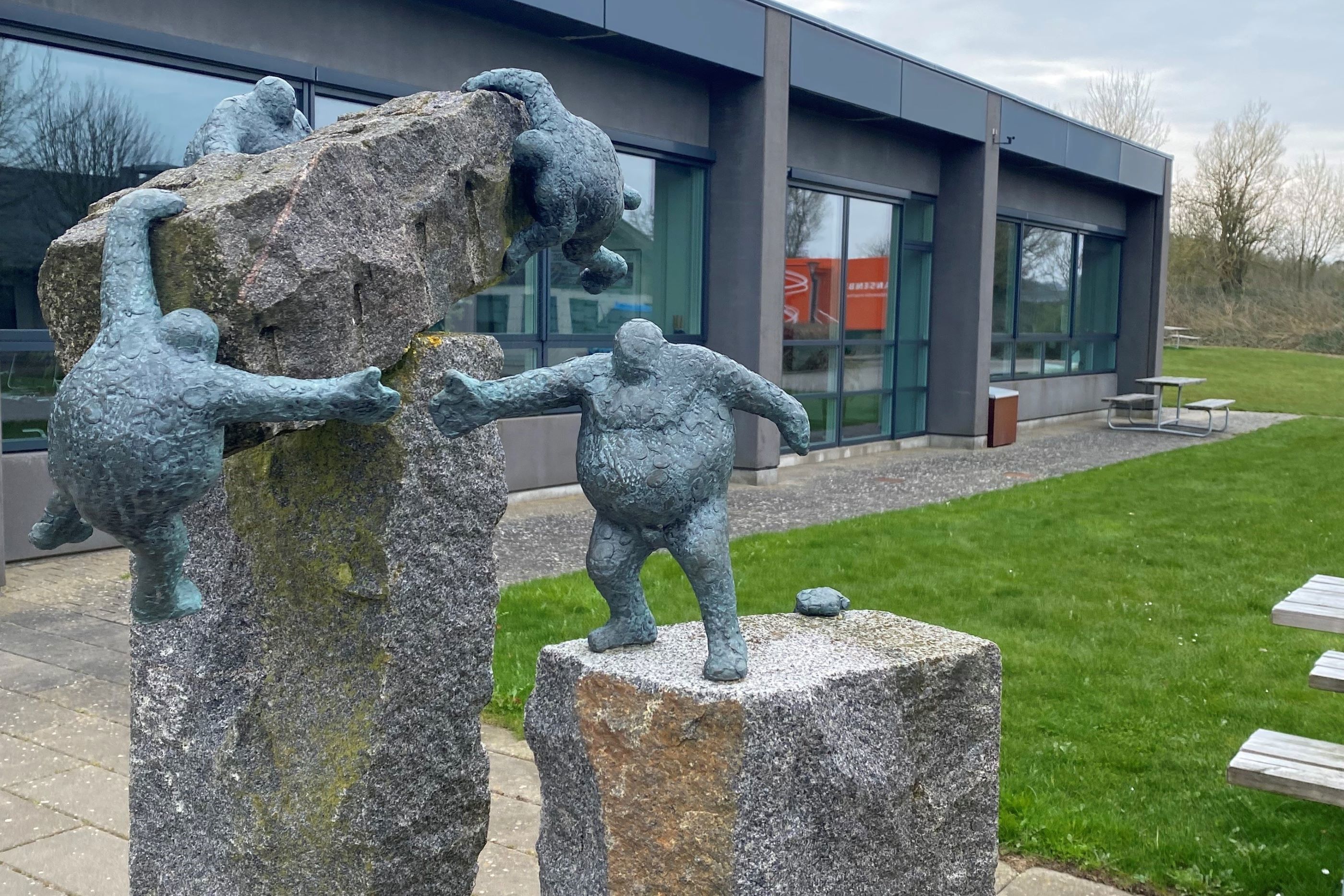 Dette fine kunstværk med små bronzemennesker, der kravler på nogle granitblokke, står foran bygning 600.